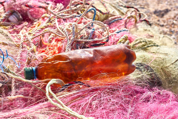 un grovigliò pasticcio di reti da pesca corda di plastica e altri detriti lavati su una spiaggia costiera. - commercial fishing net netting fishing striped foto e immagini stock