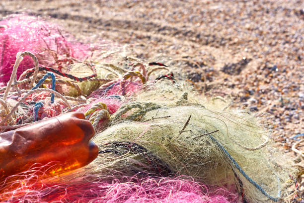 un enredado lío de redes de pesca cuerda de plástico y otros escombros lavados en una playa costera. - commercial fishing net netting fishing striped fotografías e imágenes de stock