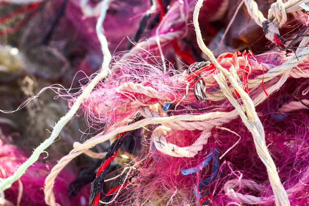 un enredado lío de redes de pesca cuerda de plástico y otros escombros lavados en una playa costera. - commercial fishing net netting fishing striped fotografías e imágenes de stock