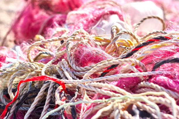 un grovigliò pasticcio di reti da pesca corda di plastica e altri detriti lavati su una spiaggia costiera. - commercial fishing net netting fishing striped foto e immagini stock