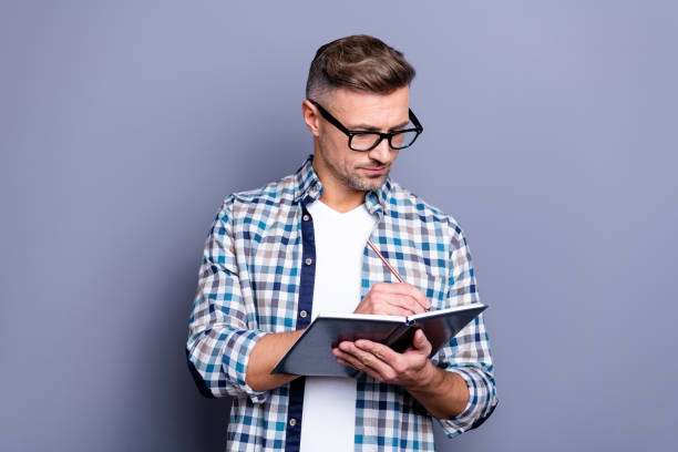 istock Close up photo handsome attractive he him his guy hands arms hold notebook making notes carefully author have inspiration clever smart wear specs casual plaid checkered shirt isolated grey background 1157097235