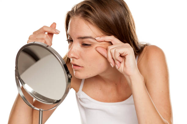 istock Young woman checking her wrinkles on her eyes 1157097888