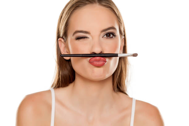 young beautiful girl posing with makeup brush on white backgeound
