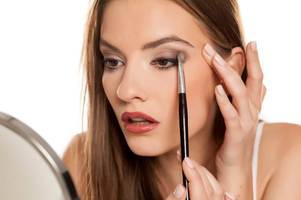 istock young beautiful girl apllying eyeshadow with makeup brushe on white backgeound 1157097950