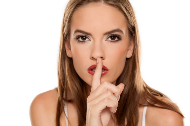 istock Beautiful girl with finger over her lips on white background 1157099095