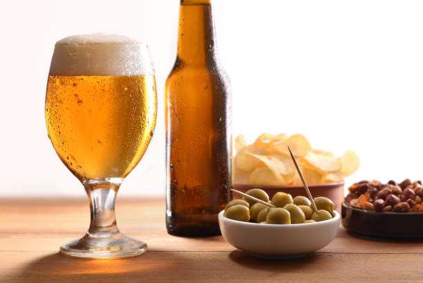 istock Glass of cold beer with appetizer on table white background 1157099449