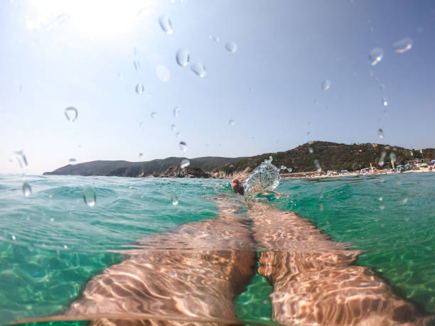 Human legs and feet, man floating in clear sea. Personal perspective. Neos Marmaras, Greece.