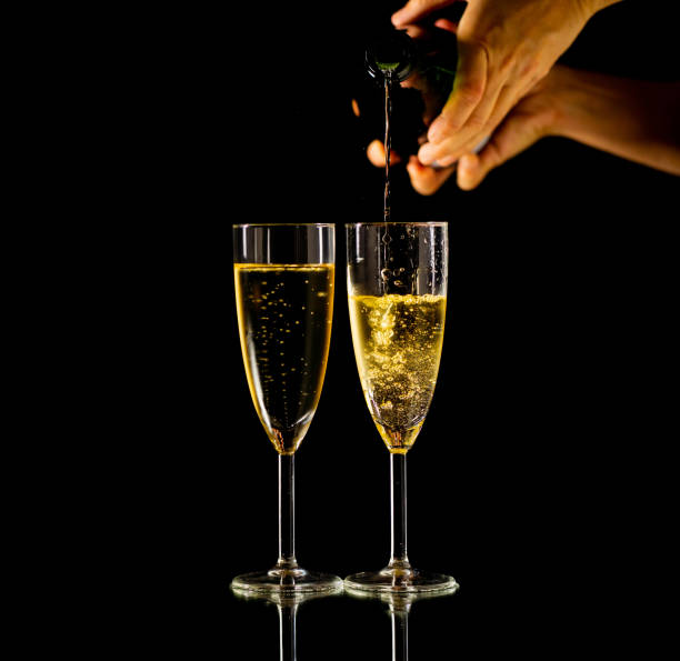 dois vidros com o champanhe que derrama do frasco pronto para brindar no conceito da celebração em anos novos dia dos valentim do natal e épocas felizes isolados no fundo preto espaço da cópia e luz do estúdio. - cork champagne isolated celebration - fotografias e filmes do acervo