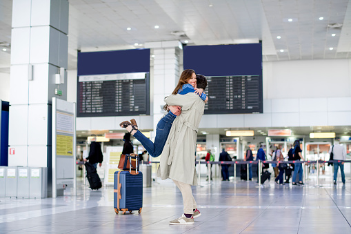 Hugging couple in international airport, Sad women