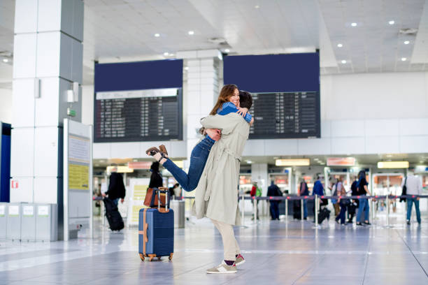 Hugging couple in international airport Hugging couple in international airport, Sad women airport hug stock pictures, royalty-free photos & images