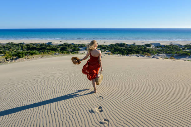 Woman on the sand goes to the sea on foot.