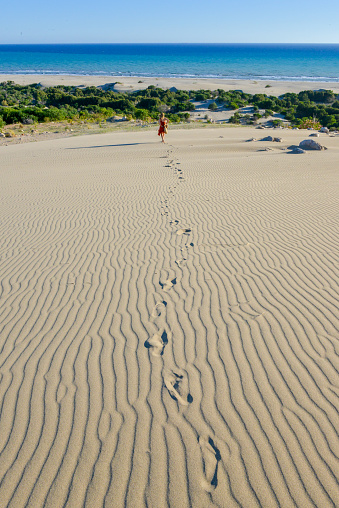 Couple walking on the path of bollard-lined sandy dune crossing near the beach in late evening light with blue sky, Hoek van Holland, Netherlands. High quality photo