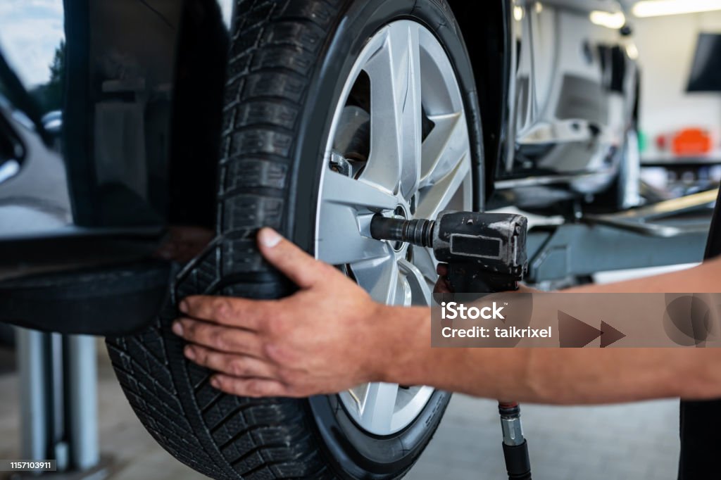 Mechanic changes a tire in a repair shop, Germany Germany: A mechanic changes a tire in a car repair shop. Tire - Vehicle Part Stock Photo