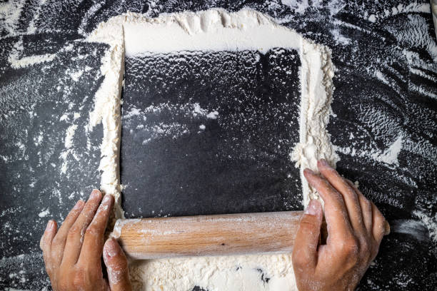 istock Female hands keep rolling pin with flour on dark table. Baking background. Flour, cooking and bake concept 1157104082