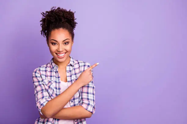 Portrait of her she nice charming cute attractive lovely cheerful wavy-haired, girl in checked shirt showing aside ad advert product copy space isolated over violet purple pastel background