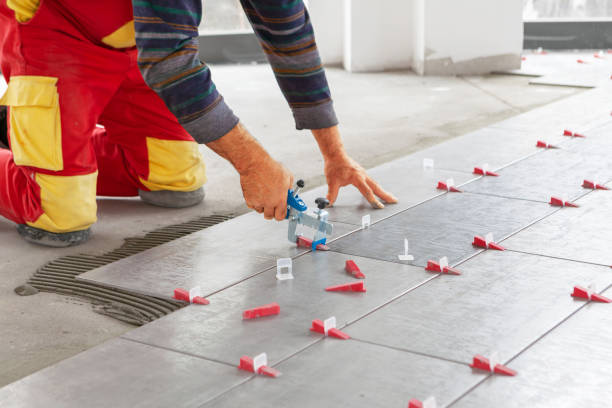 Ceramic Tiles. Tiler placing ceramic wall tile in position over adhesive with lash tile leveling system stock photo