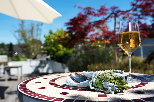 Sun terrace in summer with mediterranean table decoration and a glass white wine