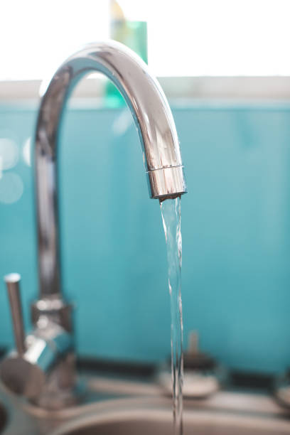 istock Water flowing from a kitchen faucet into the sink 1157106360