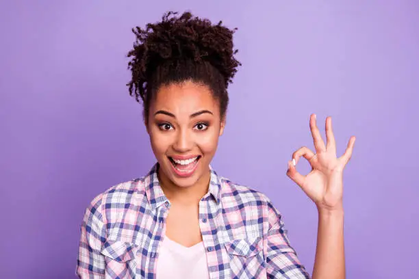 Close-up portrait of nice charming cute attractive lovely cheerful cheery optimistic, wavy-haired girl in checked shirt showing ok-sign good mood ad advert isolated over violet purple pastel background