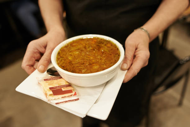 Cropped shot of an unrecognizable waiter serving a soup in a cafe during the day