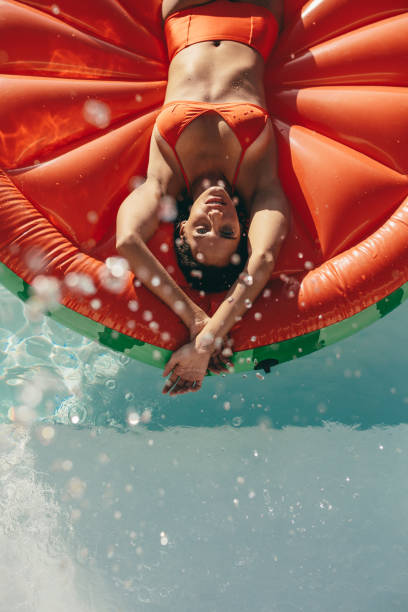 プールで膨脹可能なマットレスで日光浴する女性 - floating on water women swimming pool water ストックフォトと画像