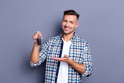 Portrait of his he nice attractive confident cheerful glad bearded guy wearing, checked shirt holding in hand remote lock alarm controller bank leasing isolated over blue pastel background
