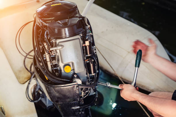 mechanic repairing inflatable motorboat engine at boat garage. ship engine seasonal service and maintenance. vessel motor with open cover - outboard motor imagens e fotografias de stock