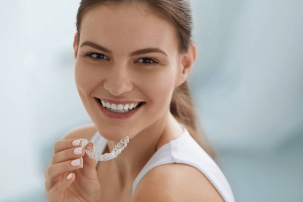 Teeth whitening. Woman with healthy teeth using removable braces stock photo
