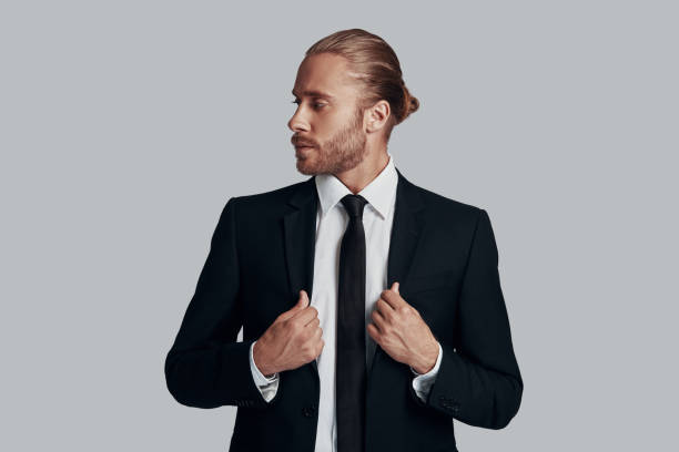 istock Good looking entrepreneur. Handsome young man in full suit adjusting jacket while standing against grey background 1157118616