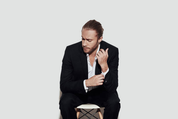 istock Solution is close. Handsome young man in full suit adjusting sleeve while sitting against grey background 1157121118