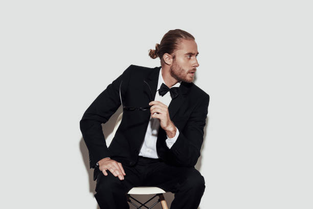 istock Taking time to think. Charming young man in full suit looking away while sitting against grey background 1157121159