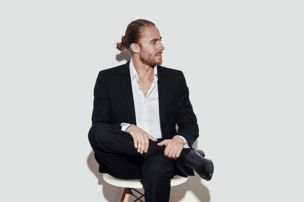 istock Time to make decision. Handsome young man in full suit looking away while sitting against grey background 1157121266