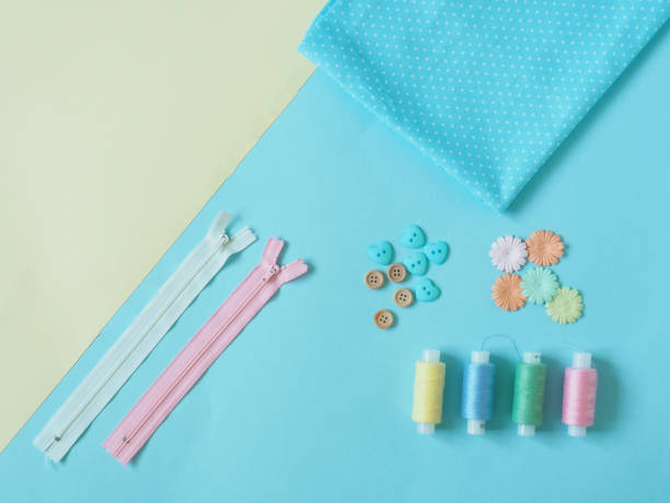istock Spools of thread, buttons, zippers, fabric. Accessories for sewing on blue and yellow background. The Duo's backgrounds. Set for needlework in the top view. 1157121328