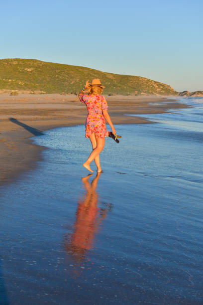 istock Woman walking on the beach at sunset. 1157121821