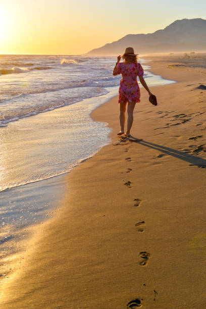 istock Woman walking on the beach at sunset. 1157124419