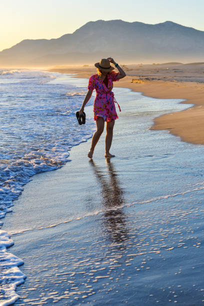 istock Woman walking on the beach at sunset. 1157124499