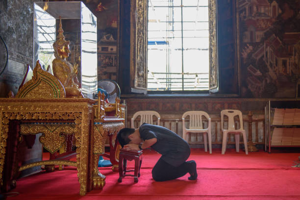 Young Asian boy praying to Buddha in Wat Suthat