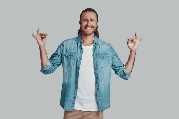 istock Begging for... Handsome young man gesturing and smiling while standing against grey background 1157127204
