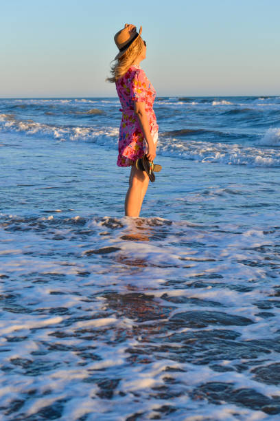 Woman walking on the beach at sunset.