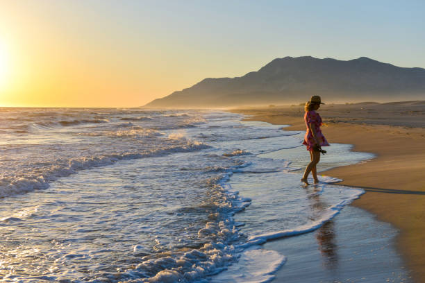 istock Woman walking on the beach at sunset. 1157128049