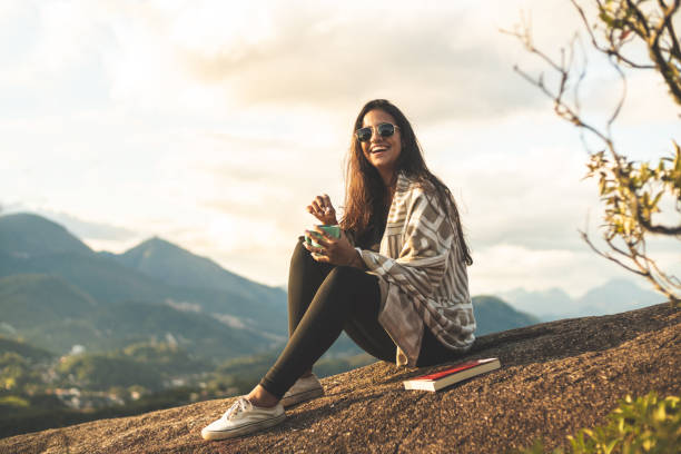 Young woman reading and drinking coffee in the mountains (Pedra do Cortiço) in the Serra dos Orgãos National Park, Rio de Janeiro, Brazil Camping, Rio de Janeiro, Coffee - Drink, Coffee Cup, Reading travel destinations 20s adult adventure stock pictures, royalty-free photos & images
