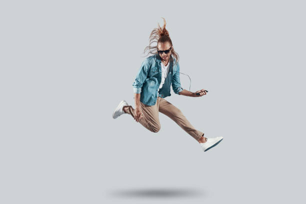 Like a rock star. Full length of handsome young man playing imaginary guitar while hovering against grey background