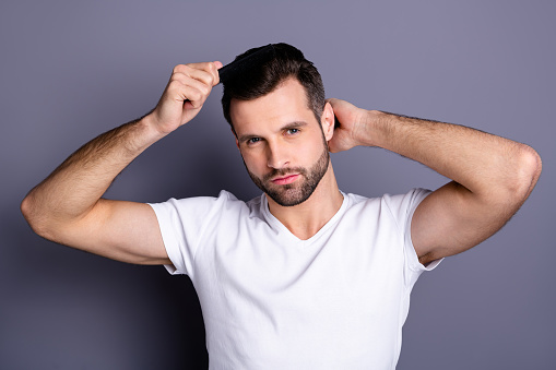 Close up photo amazing he him his macho perfect appearance hands arms plastic hair, styling brush take care hairdo after barber shop stylist visit wear casual white t-shirt isolated grey background