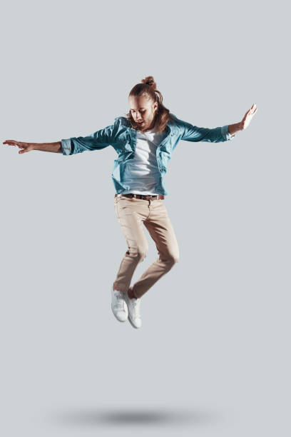istock Mid-air fun. Full length of handsome young man keeping arms outstretched while hovering against grey background 1157129430