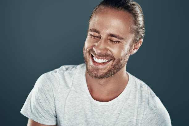 istock Overheard something funny. Good looking young man smiling while standing against grey background 1157129635
