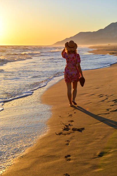 istock Woman walking on the beach at sunset. 1157129832