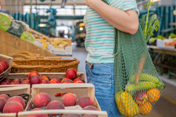 Fruits and Vegetables in a cotton mesh reusable bag, Zero Waste Shopping concept at public outdoors market.