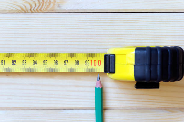 il metro esteso e una semplice matita indicano la gradazione del metro su cento centimetri. - tape measure yellow long instrument of measurement foto e immagini stock