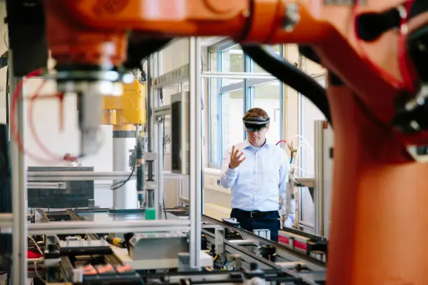 engineer works with a HoloLens place a virtual robotic arm into the production line