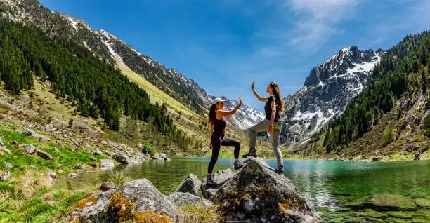 Two female Friends celebrating  high five in the mountains